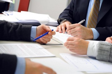 people-in-suits-looking-over-papers-on-desk